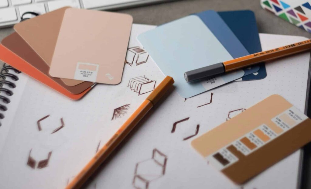 A designer's desk layout featuring color swatches, logo design sketches in a notebook, and a keyboard, representing a strategic business rebranding process.