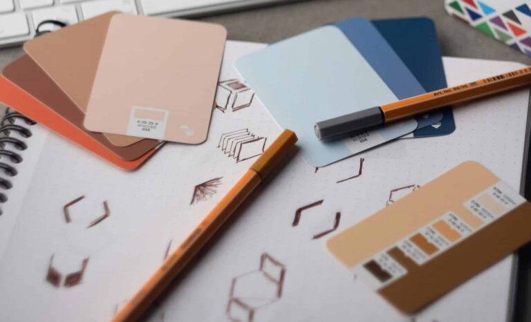 A designer's desk layout featuring color swatches, logo design sketches in a notebook, and a keyboard, representing a strategic business rebranding process.