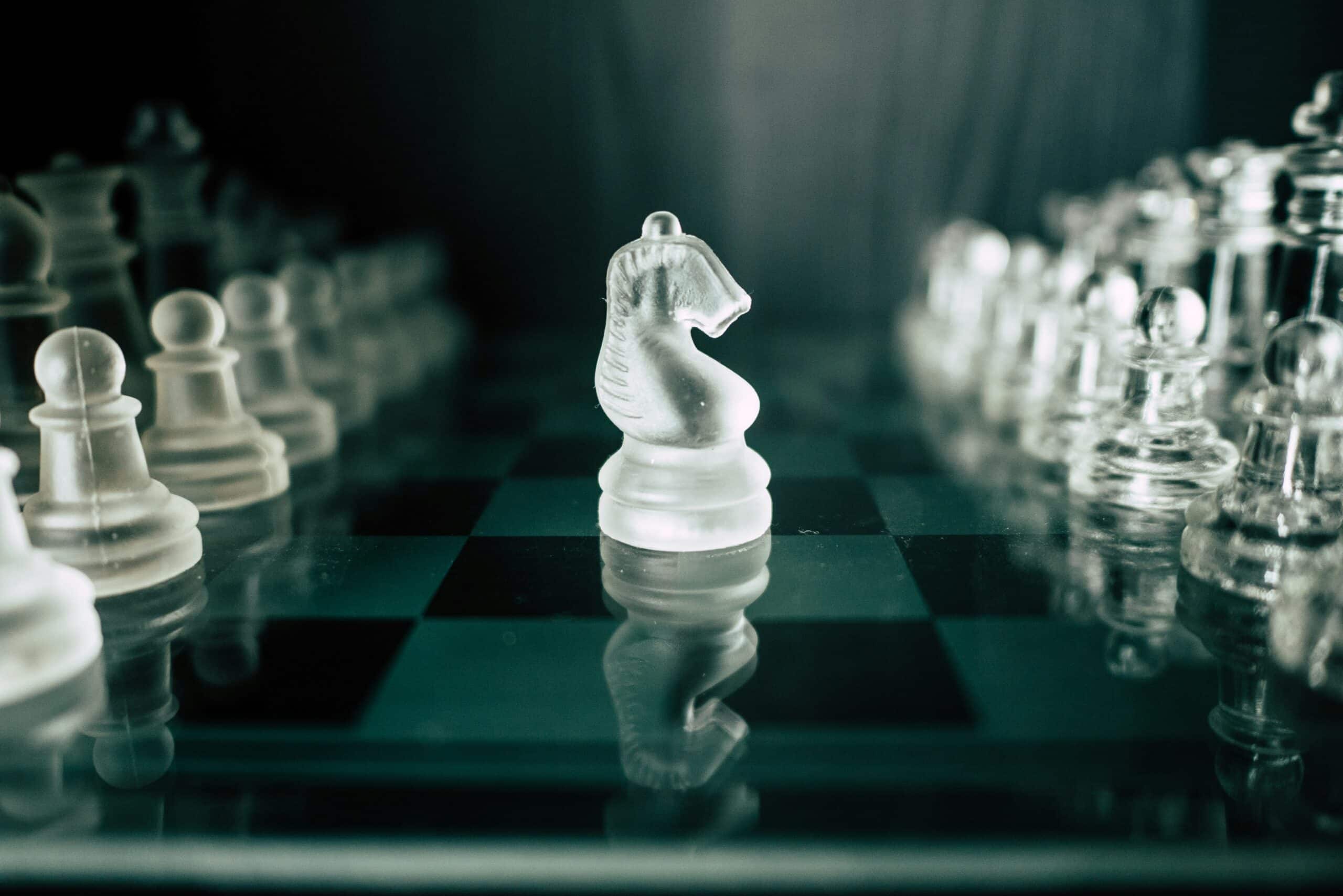 Glass knight chess piece in focus on a chessboard representing strategic marketing fundamentals and decision-making.