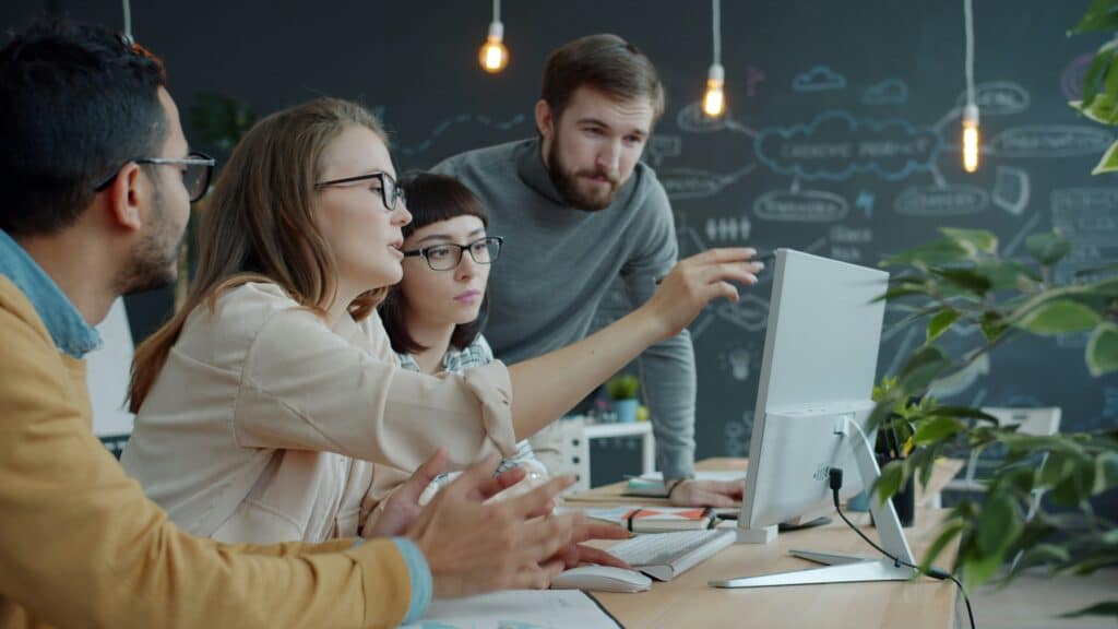 Business team reviewing marketing case studies and sales enablement materials in a conference room meeting.